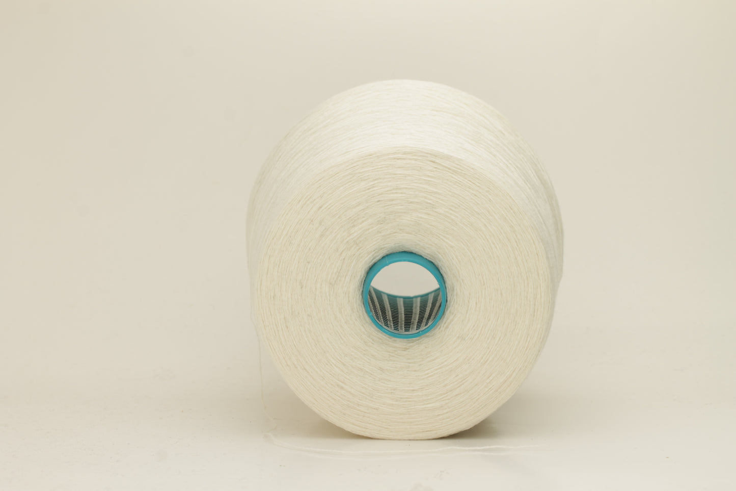 Close-up of a two-ply fine cashmere yarn, tightly twisted with a subtle matte sheen in a creamy off-white Gesso color.