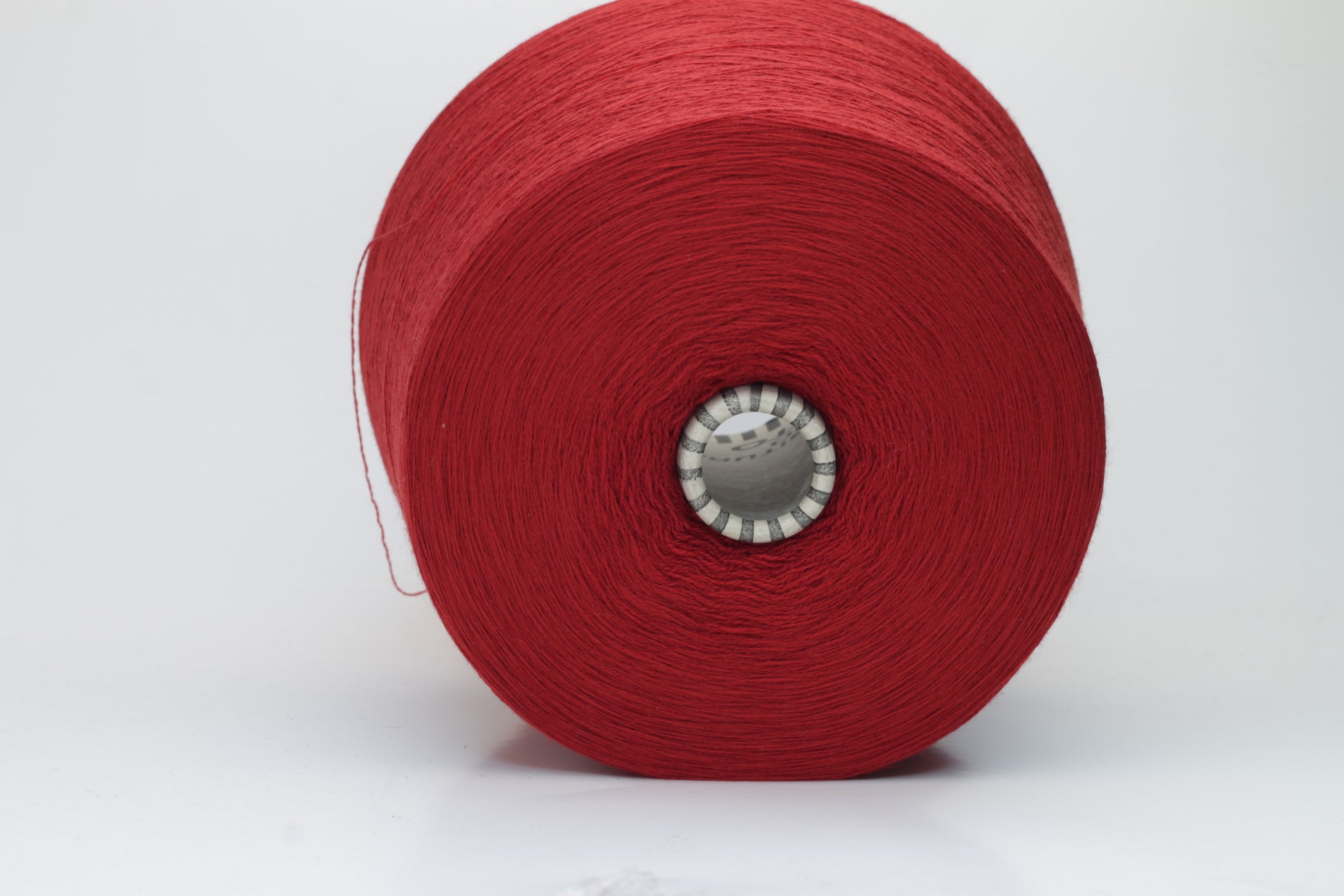 Close-up image of a vibrant red merino wool yarn skein, showcasing the smooth ply twist and subtle sheen reflecting light, with a fluffy texture.