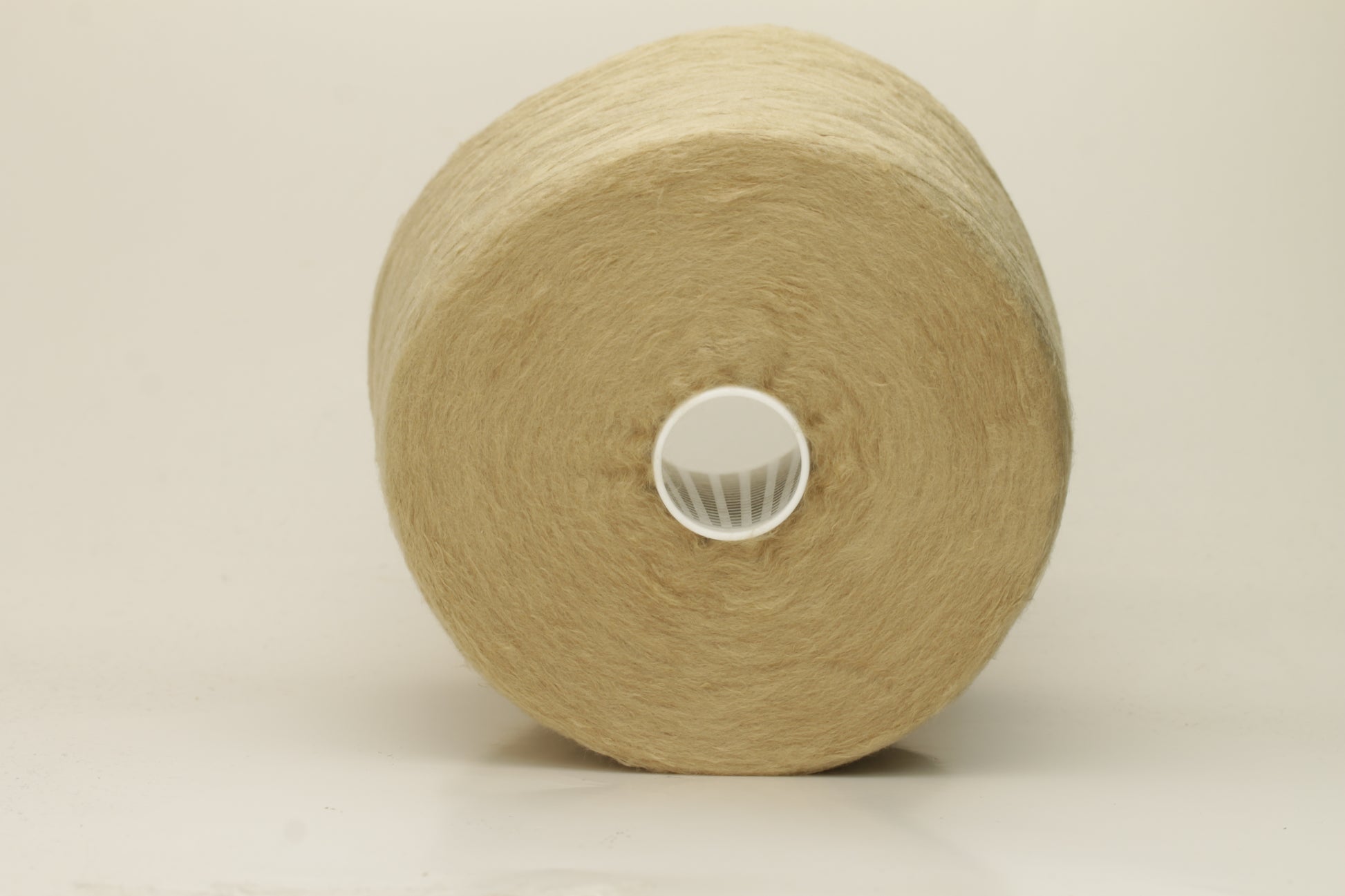 Luxurious, pristine Beige single-ply silk yarn with a smooth, uniform texture and a delicate sheen, softly coiled.