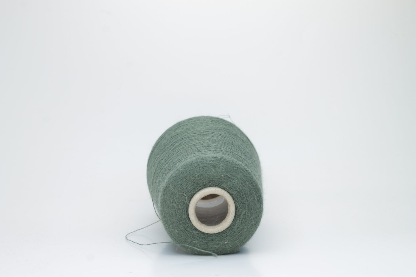 Close-up of a skein of soft, plied alpaca merino yarn in a deep green, showing subtle sheen and fine fiber halo.