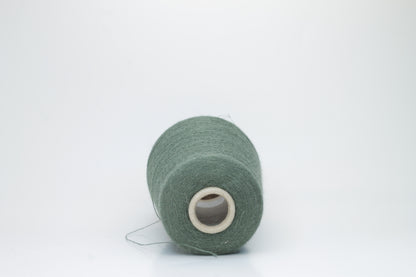 Close-up of a skein of soft, plied alpaca merino yarn in a deep green, showing subtle sheen and fine fiber halo.