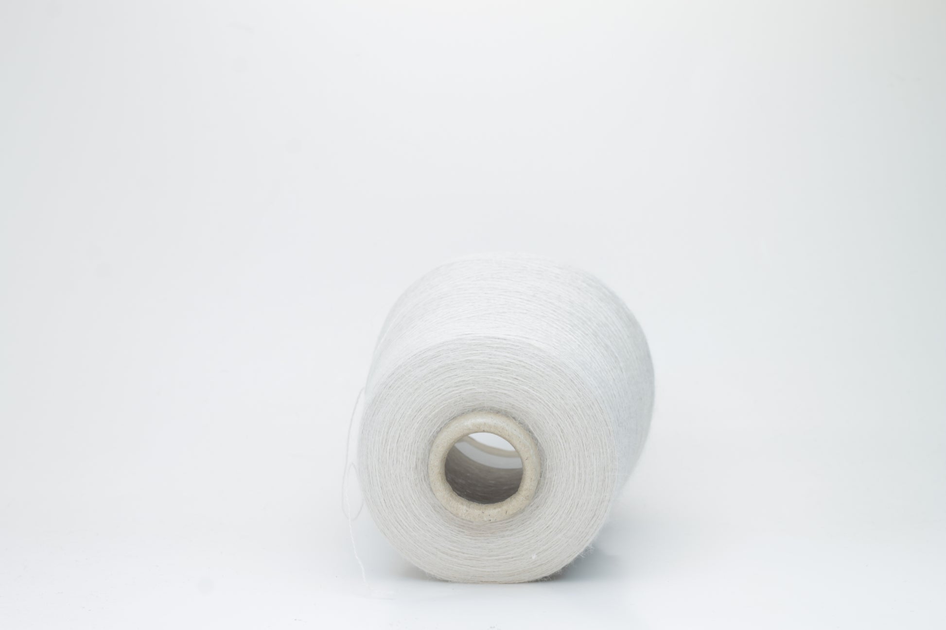 Close-up of lustrous beige 2-ply alpaca merino yarn, subtly twisted with a fine, even structure and soft, low halo.