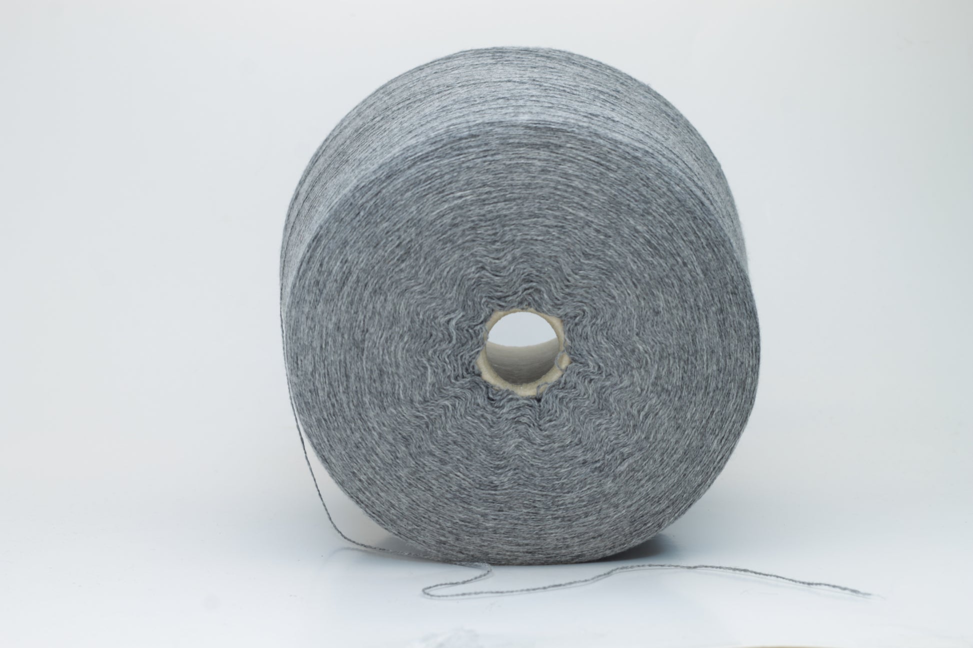 Skein of fine, two-ply cashmere yarn in a sophisticated medium gray, exhibiting a soft, subtle halo and delicate matte sheen.