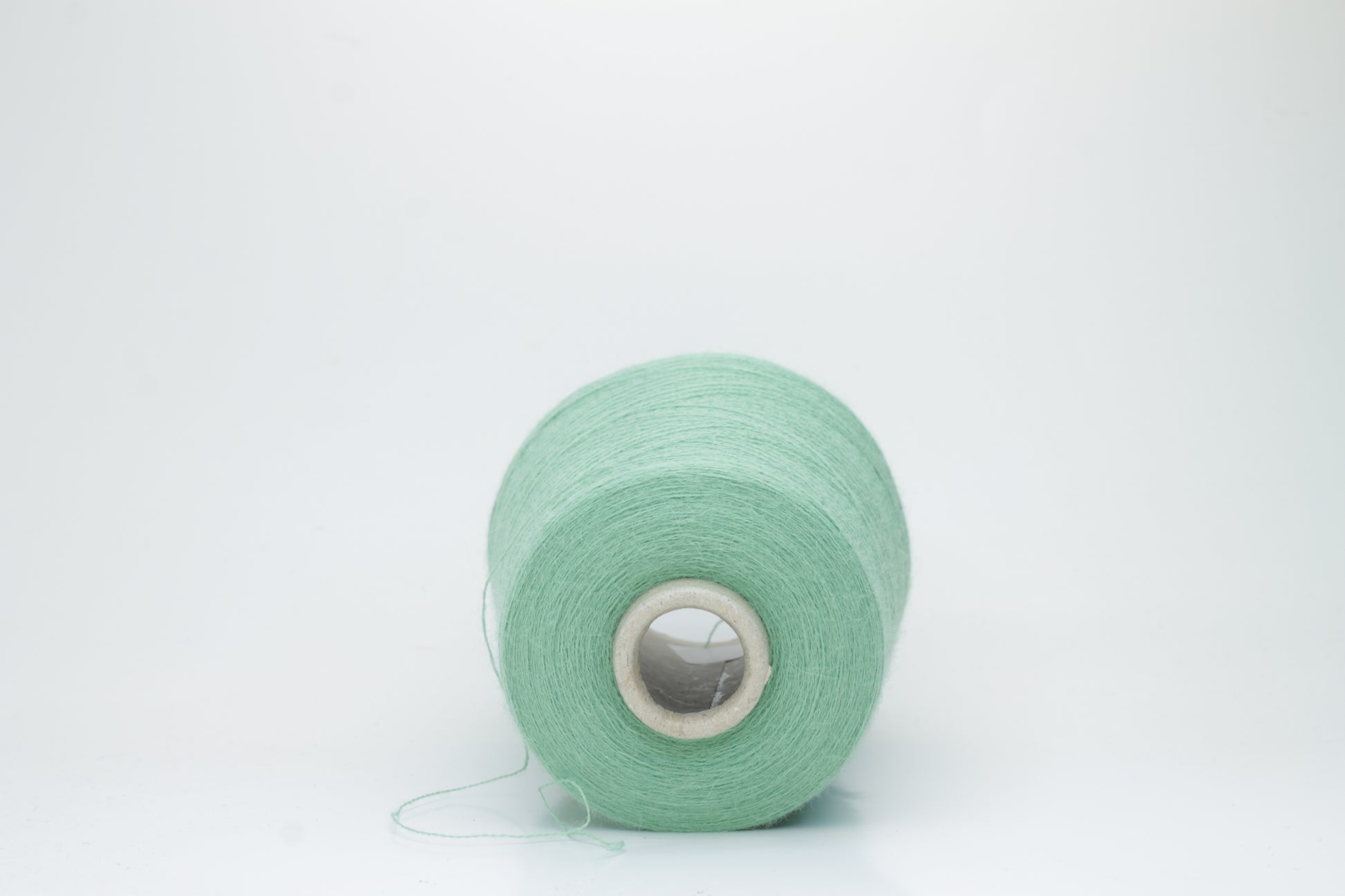 Close-up of a skein of soft, plied alpaca merino yarn in a deep green, showing subtle sheen and fine fiber halo.