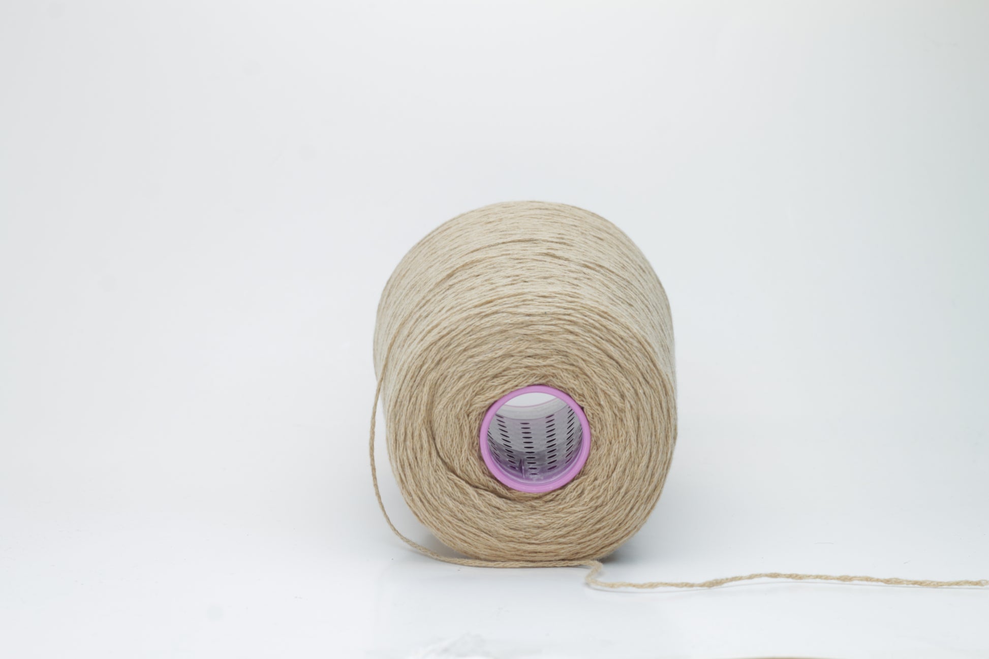 A luxuriously soft skein of pale, warm camel-colored cashmere yarn, gently twisted with a subtle halo, showcasing its delicate and fine fibers.