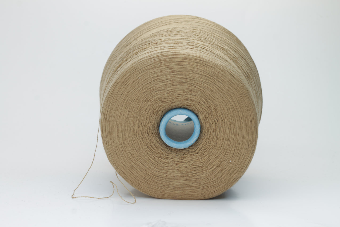 Close-up shot of a cone of creamy camel colored 100% merino yarn, showcasing the fine ply twist and subtle sheen of the fibers.