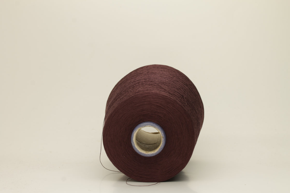 Close-up of a deep, rich espresso brown silk yarn wound in a neat cake, showcasing its smooth, lustrous surface and fine, even ply twist. The individual strands reflect light softly.
