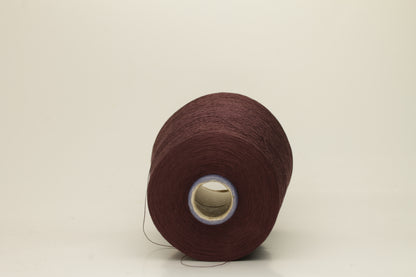 Close-up of a deep, rich espresso brown silk yarn wound in a neat cake, showcasing its smooth, lustrous surface and fine, even ply twist. The individual strands reflect light softly.