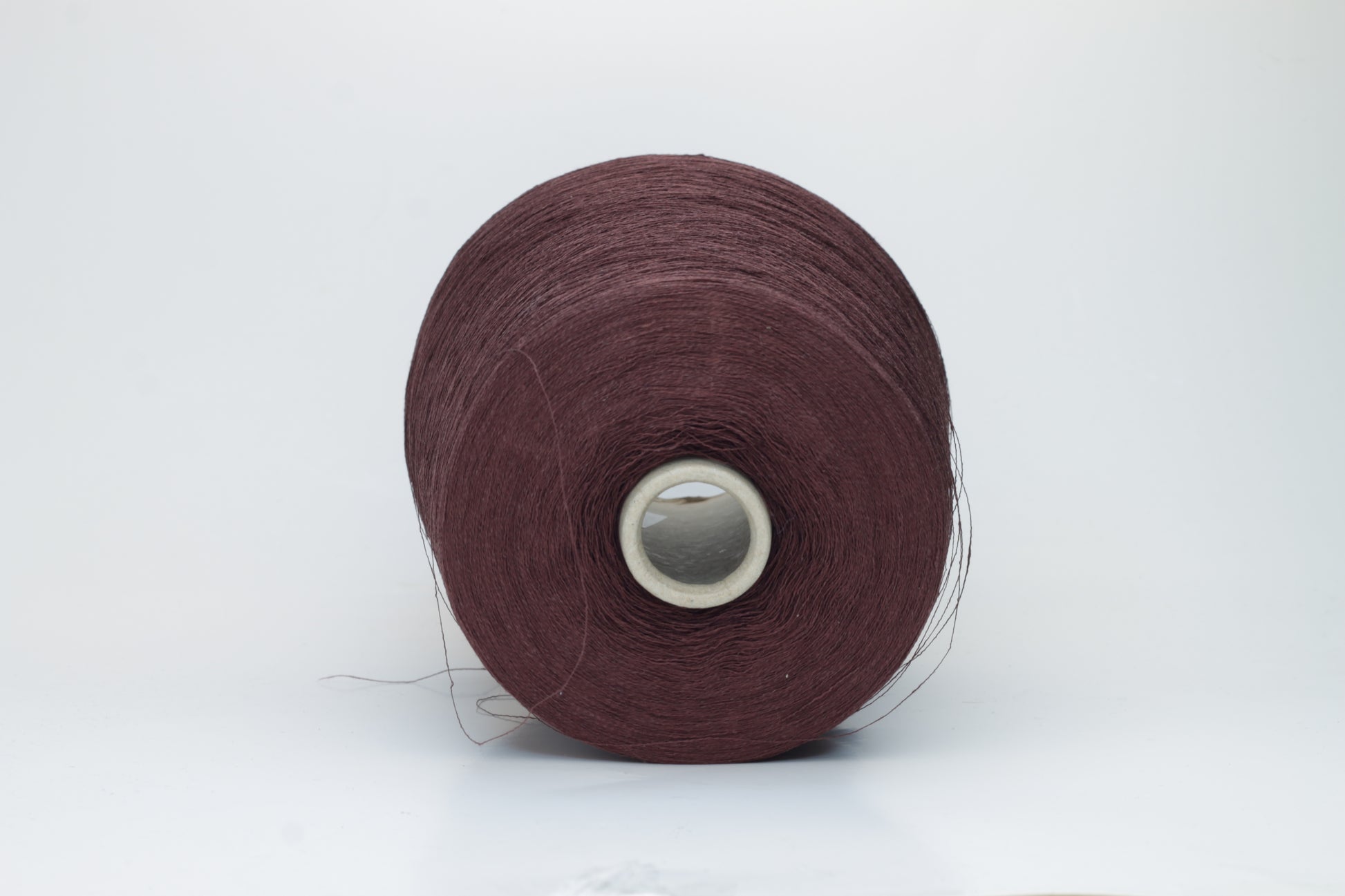 Close-up of a tightly twisted, fine-gauge yarn in a deep, warm earthy brown color, showing a subtle natural sheen from the linen fibers.