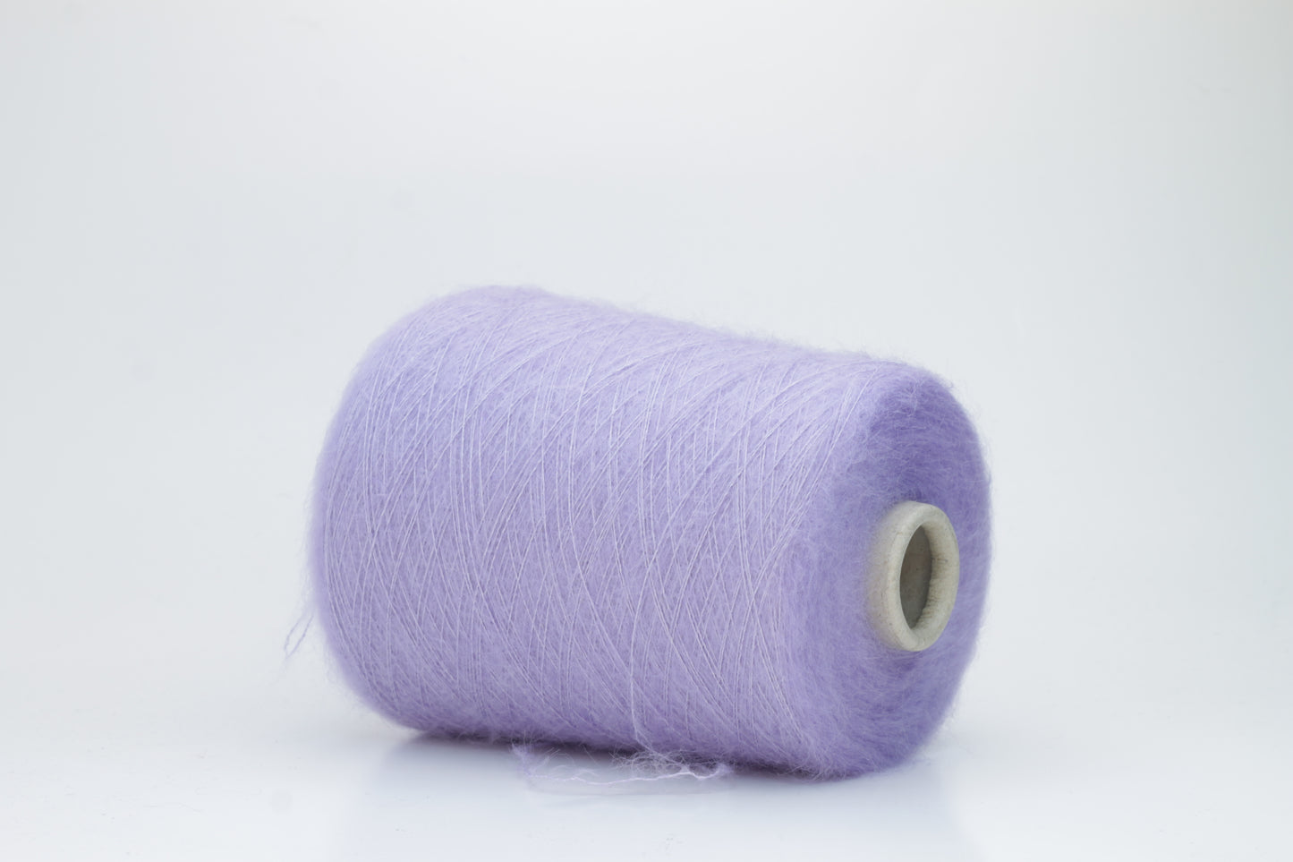 Close-up of fluffy Lila kid mohair and silk blend yarn, subtly lustrous with a soft halo, gently twisted into a fine, delicate thread.