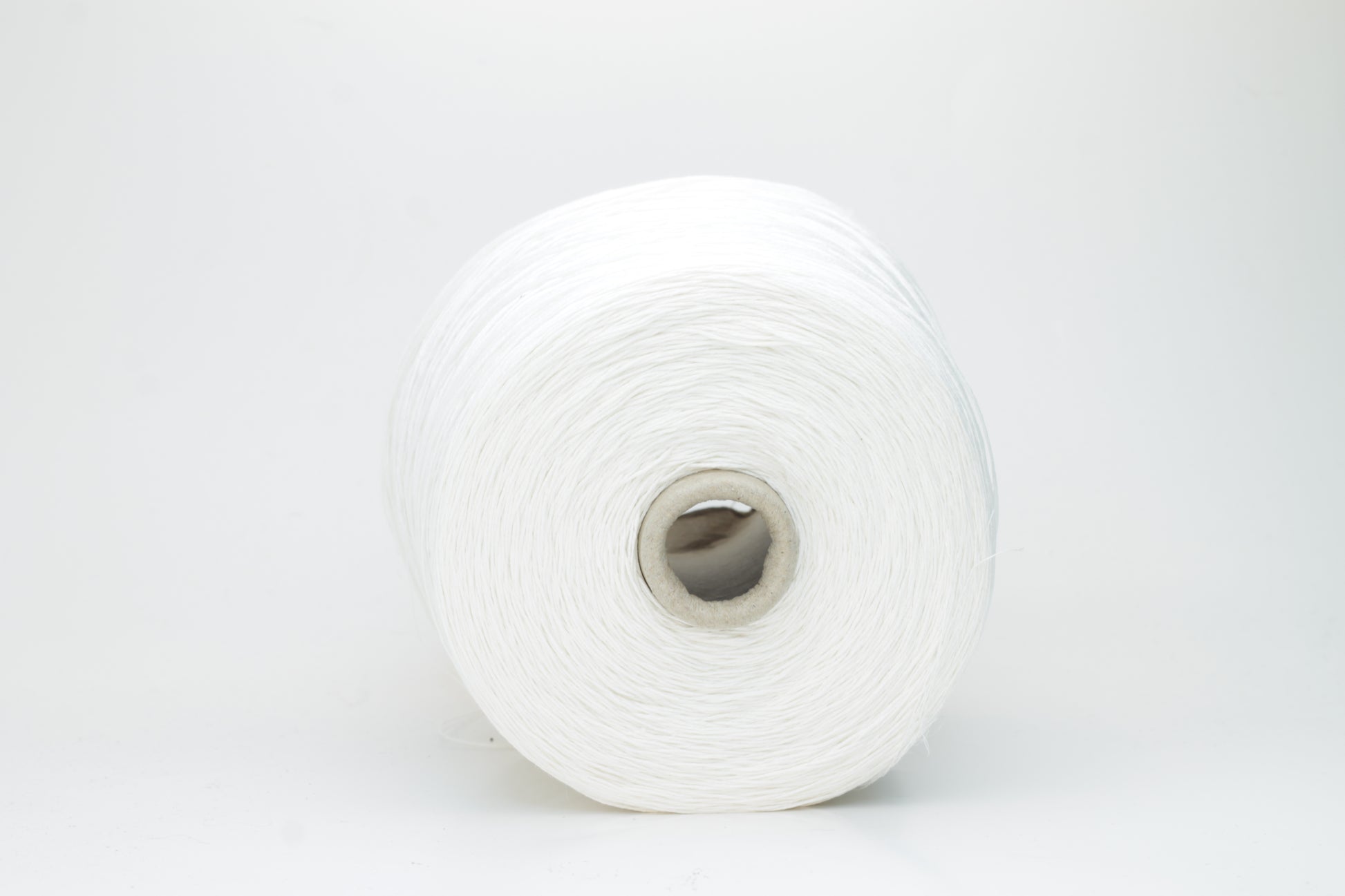 Close-up of pristine white linen and viscose blend yarn, softly twisted with a subtle sheen, showcasing its fine, smooth texture.