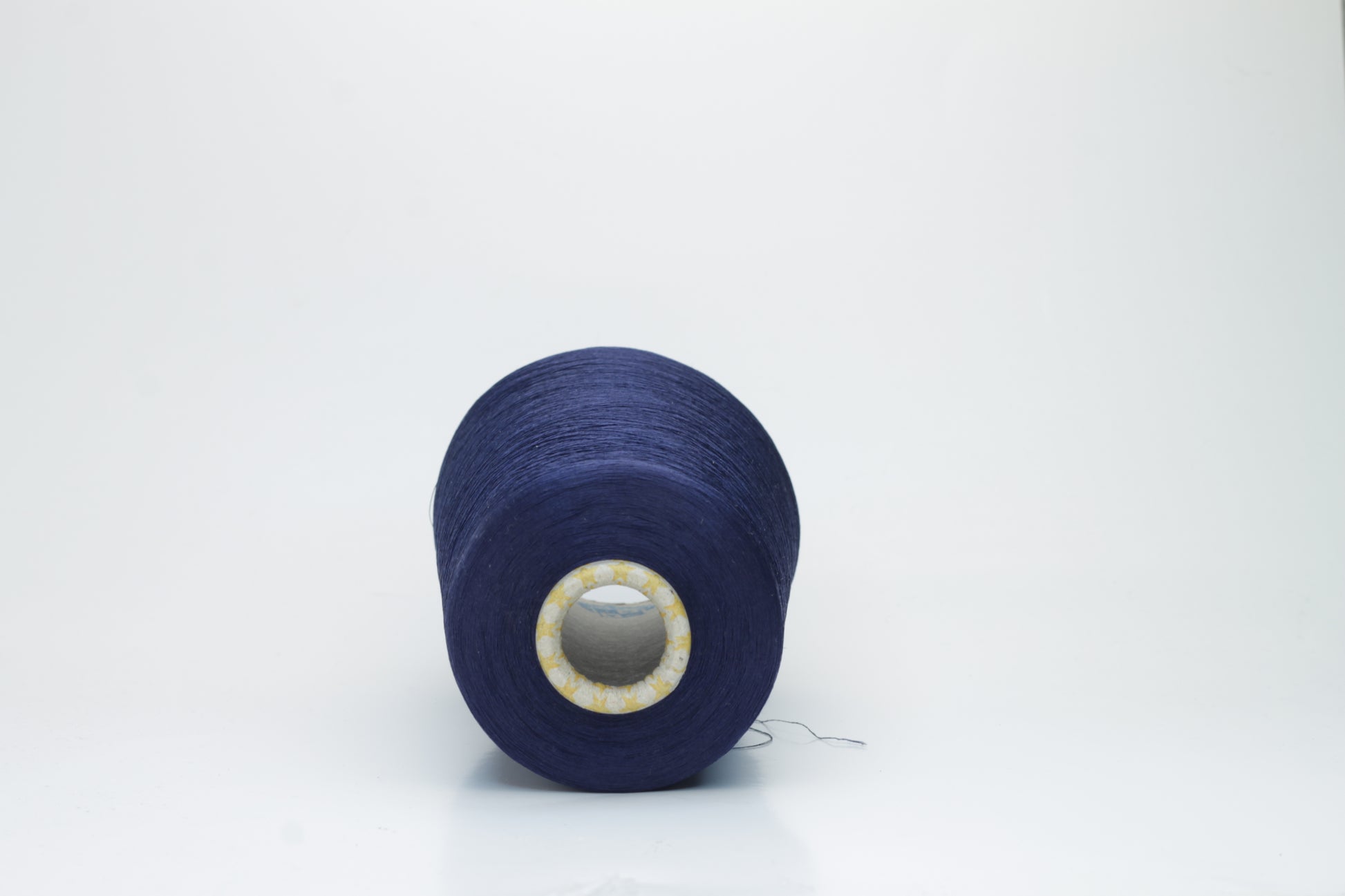 Close-up of finely spun navy blue silk yarn, gently twisted, displaying a subtle, elegant sheen. Smooth, lustrous fibers reflect light softly, hinting at fluid drape and rich color depth.