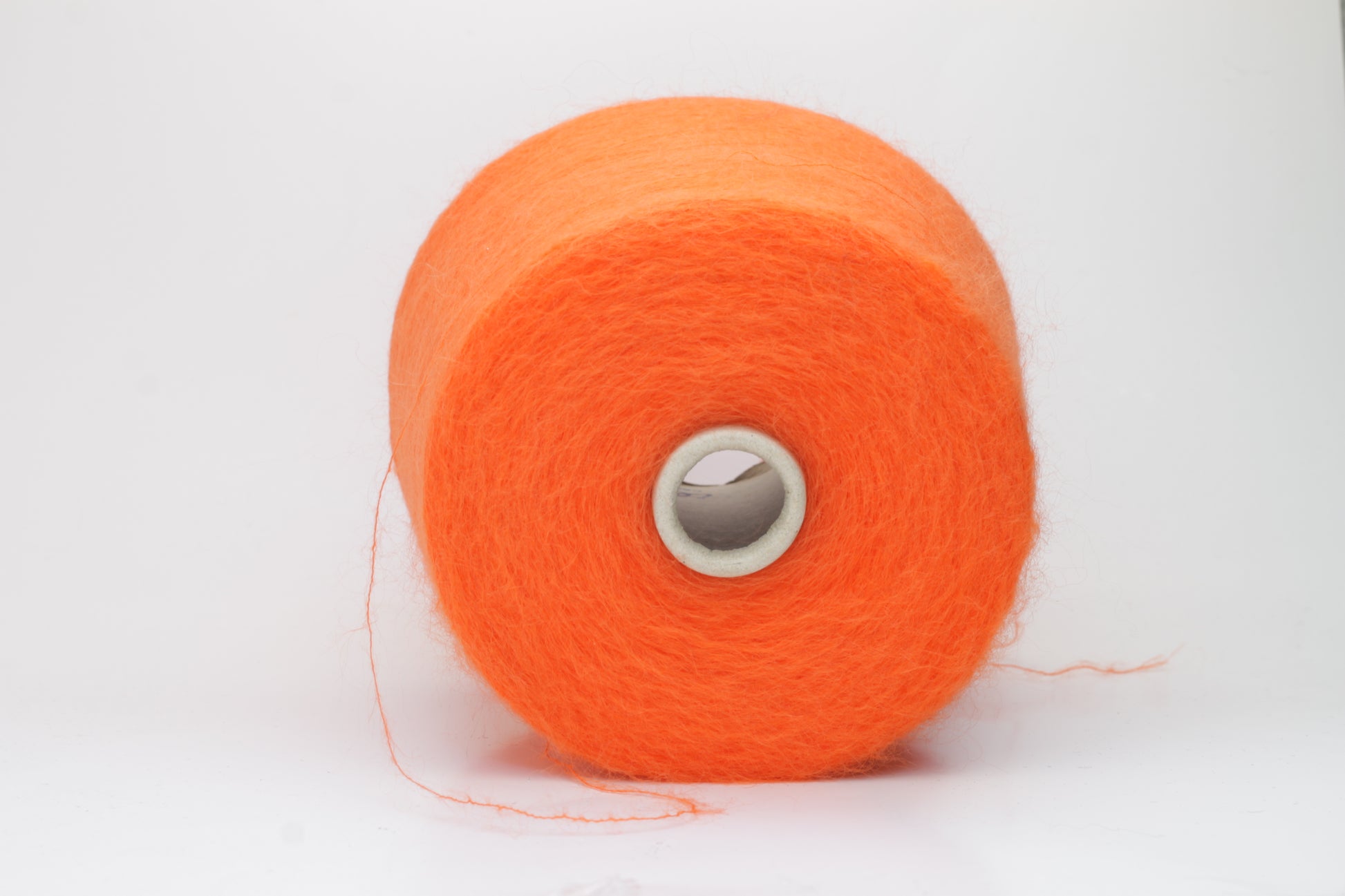 Close-up shot of vibrant orange SuperKidMohair yarn, displaying a tight ply twist and a rich, fluffy texture with noticeable sheen.