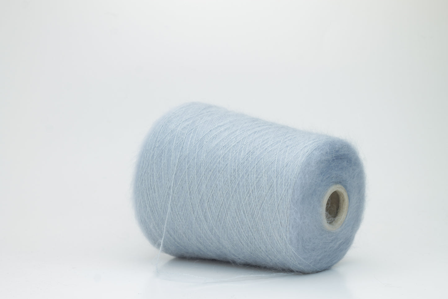 Close-up of fluffy Cielo kid mohair and silk blend yarn, subtly lustrous with a soft halo, gently twisted into a fine, delicate thread.