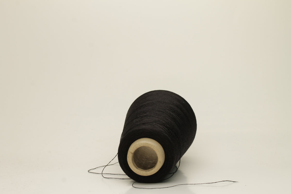 Close-up of pristine Black, finely plied 100% silk yarn, twisted smoothly to reveal a high, lustrous sheen and uniform structure.