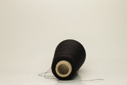 Close-up of pristine Black, finely plied 100% silk yarn, twisted smoothly to reveal a high, lustrous sheen and uniform structure.