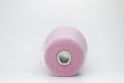 Close-up of fluffy Rosa kid mohair and silk blend yarn, subtly lustrous with a soft halo, gently twisted into a fine, delicate thread.