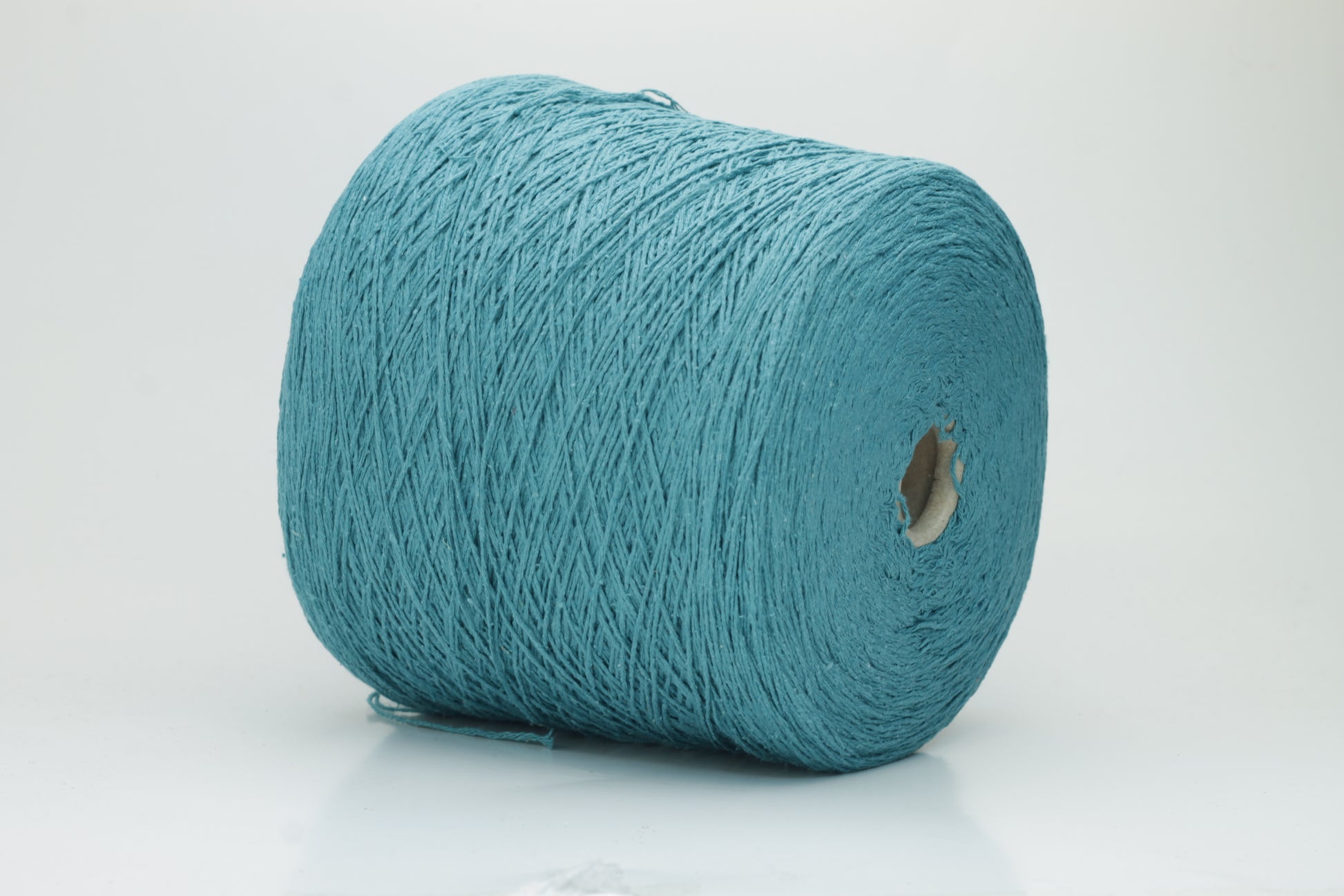 Close-up of a skein of deep petrol blue-green bourette silk yarn, showing its characteristic subtle slubs and matte texture, with a gentle, soft twist.