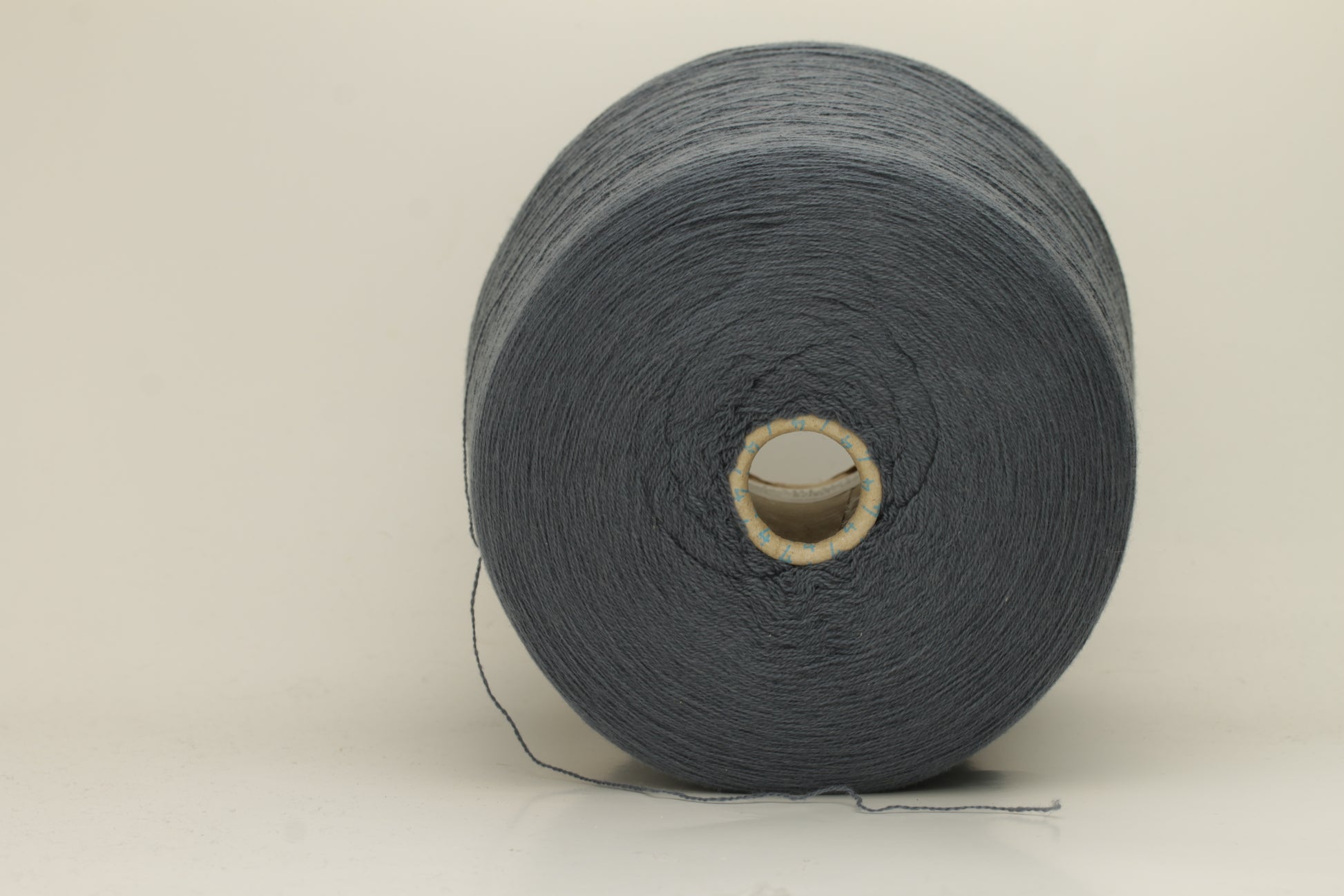 Close-up of a skein of dark, stormy blue-grey cashmere yarn with a subtle sheen. The fine, two-ply twist is visible, creating a smooth, incredibly soft thread structure that suggests luxurious warmth.