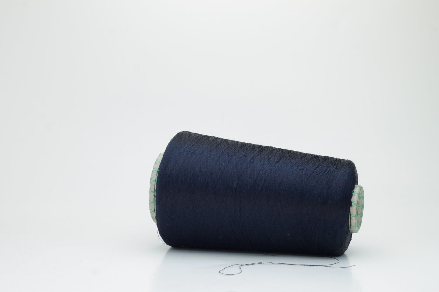 Close-up of a neatly wound spool of fine navy silk yarn, exhibiting a smooth, tightly twisted two-ply structure and a subtle, elegant sheen under direct light. The deep blue color appears rich and consistent.