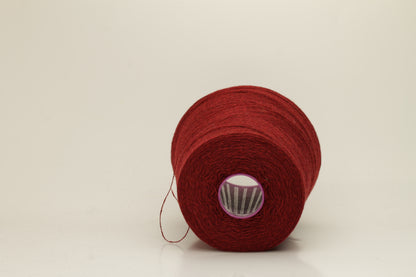 Close-up of fine 2-ply pure cashmere yarn in a rich, velvety burgundy red with subtle rosy undertones, showing its soft sheen and delicate fluff.