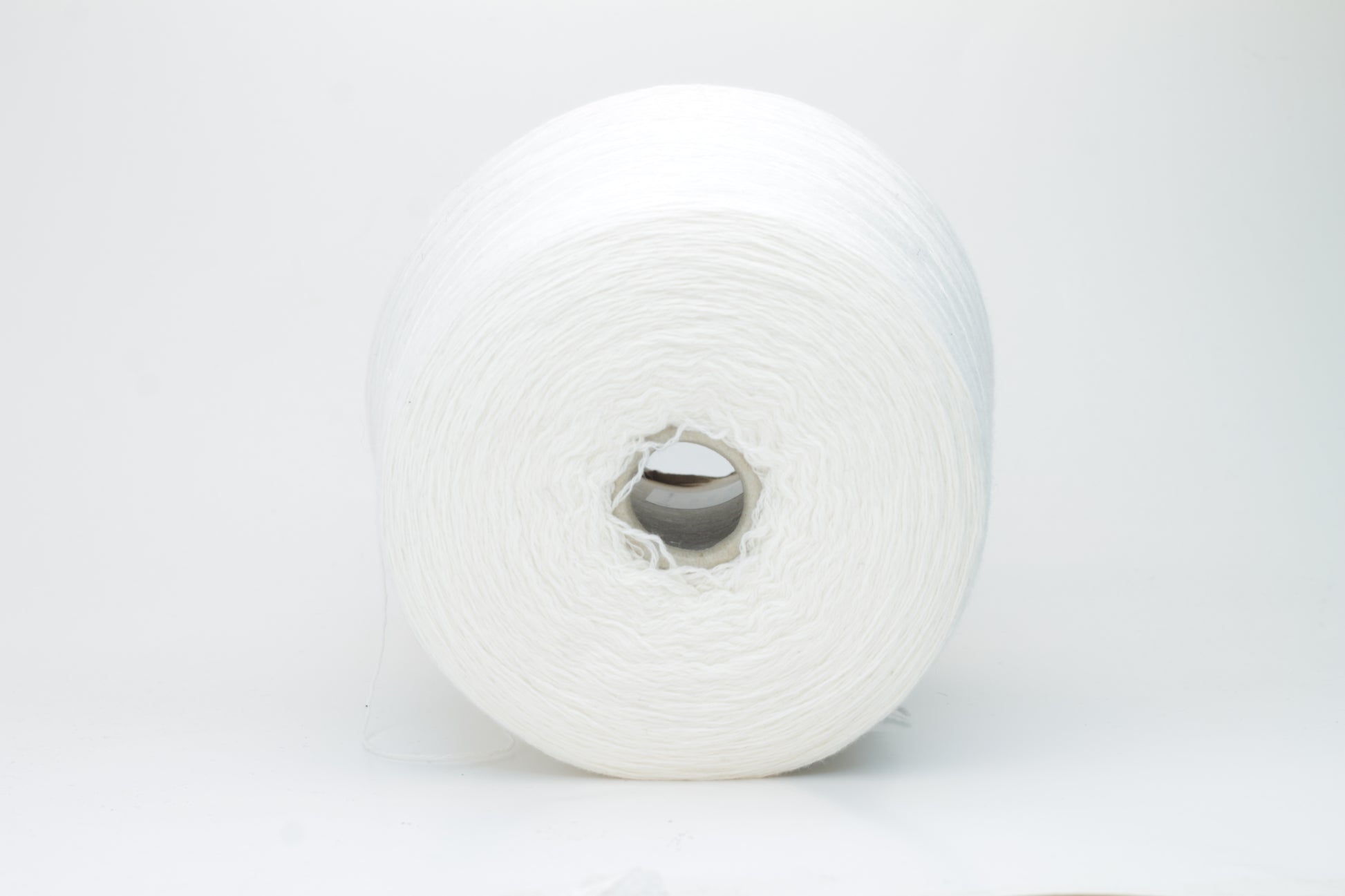 Close-up of a pure white cashmere yarn skein, showcasing its soft, slightly fluffy texture and subtle sheen with a gently twisted, fine two-ply structure.