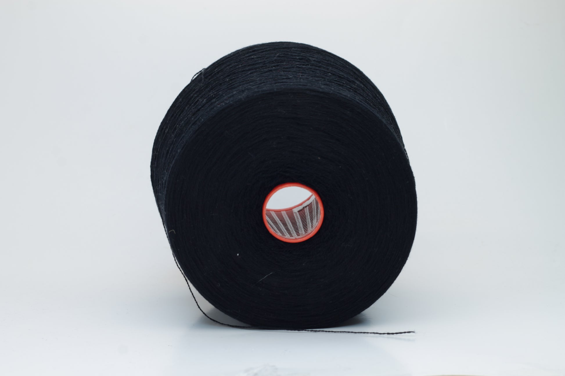 Close-up of a deep black, two-ply cashmere yarn, exhibiting a soft, even twist and a subtle, rich sheen under natural light, indicating its luxurious texture.