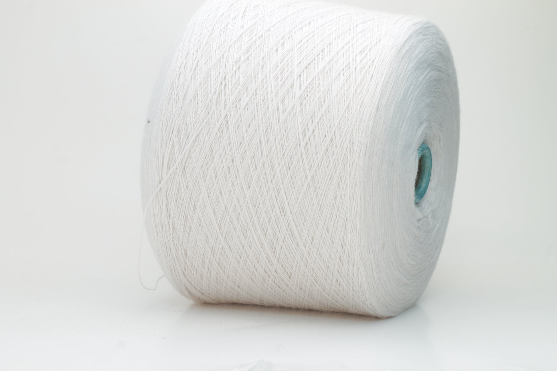 Close-up shot of creamy white Zegna Baruffa merino yarn, showcasing a dense, twisted ply structure and subtle sheen, with a fluffy texture inviting tactile exploration.