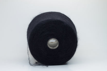 Close-up of fluffy Black kid mohair and silk blend yarn, subtly lustrous with a soft halo, gently twisted into a fine, delicate thread.