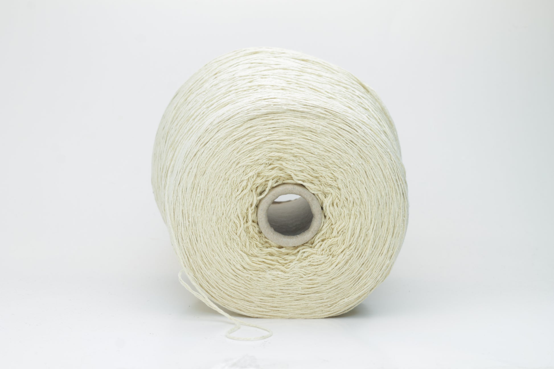 Close-up of creamy 'Giallino' Silk Bourette yarn, showcasing its incredibly fine ply twist and subtle sheen. The yarn has a smooth, almost liquid texture with abundant fluffiness.