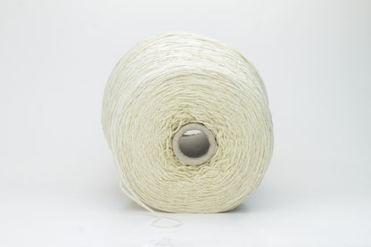 Close-up of creamy 'Giallino' Silk Bourette yarn, showcasing its incredibly fine ply twist and subtle sheen. The yarn has a smooth, almost liquid texture with abundant fluffiness.