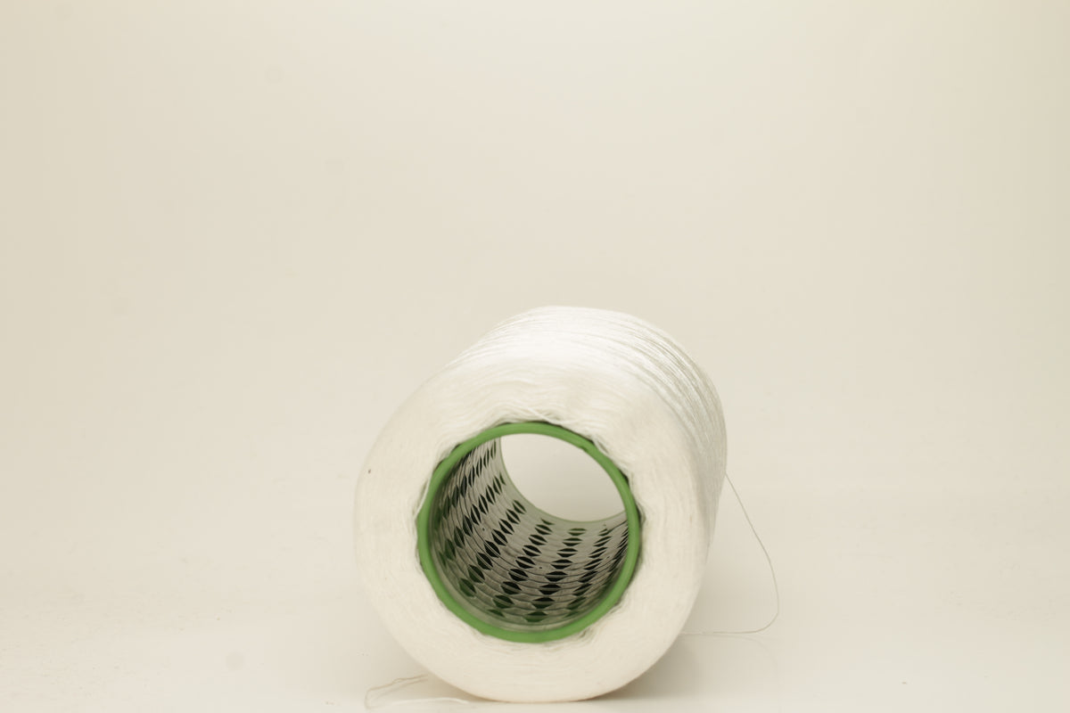 Close-up of pristine white, finely plied 100% silk yarn, twisted smoothly to reveal a high, lustrous sheen and uniform structure.