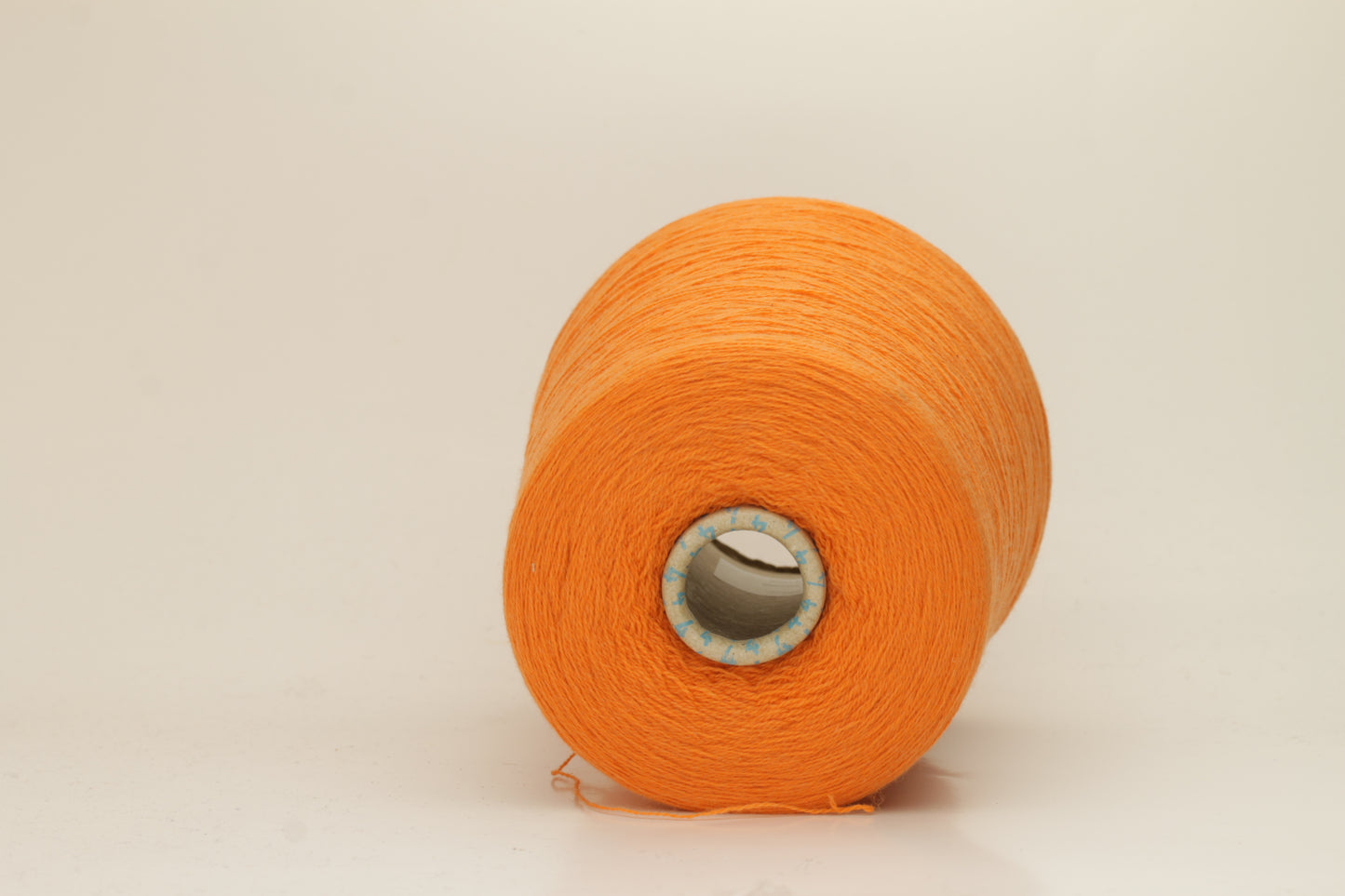 Close-up of fluffy, deeply saturated Jaffa orange cashmere yarn, showing its soft, slightly twisted two-ply structure and delicate sheen.