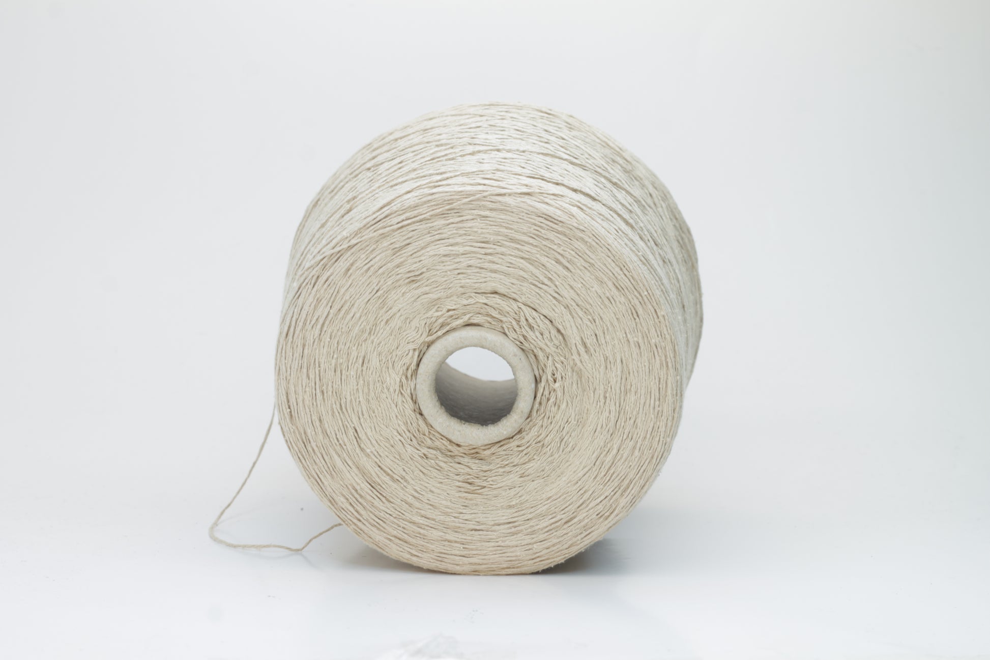 Close-up of a skein of natural beige 100% silk bourette yarn, showing its characteristic slubby, textured, slightly uneven threads.