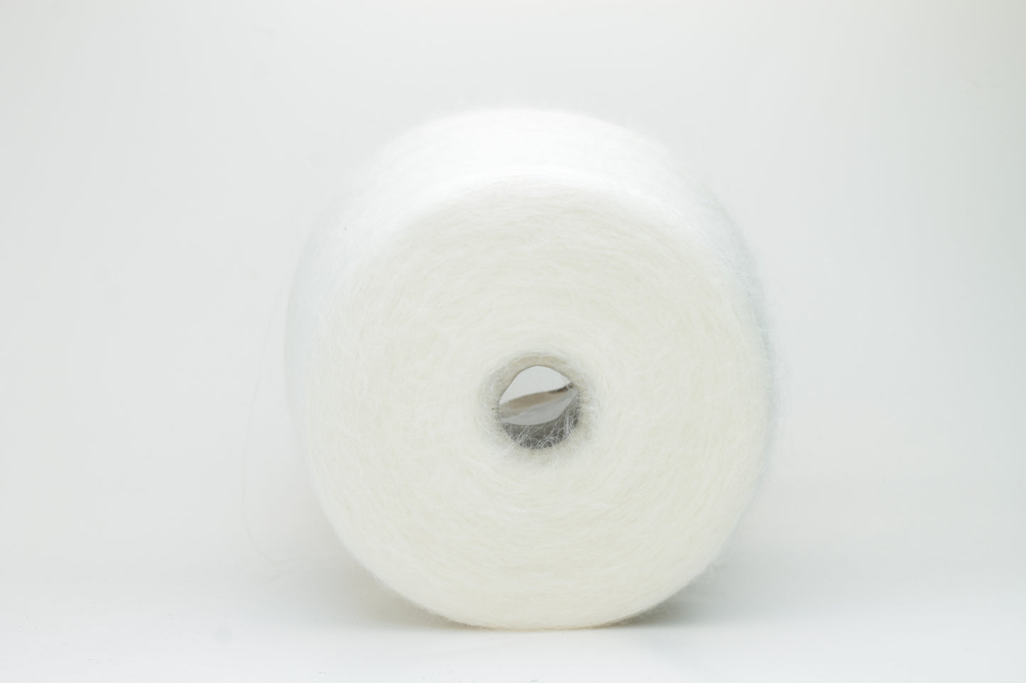 Close-up of fluffy white kid mohair and silk blend yarn, subtly lustrous with a soft halo, gently twisted into a fine, delicate thread.
