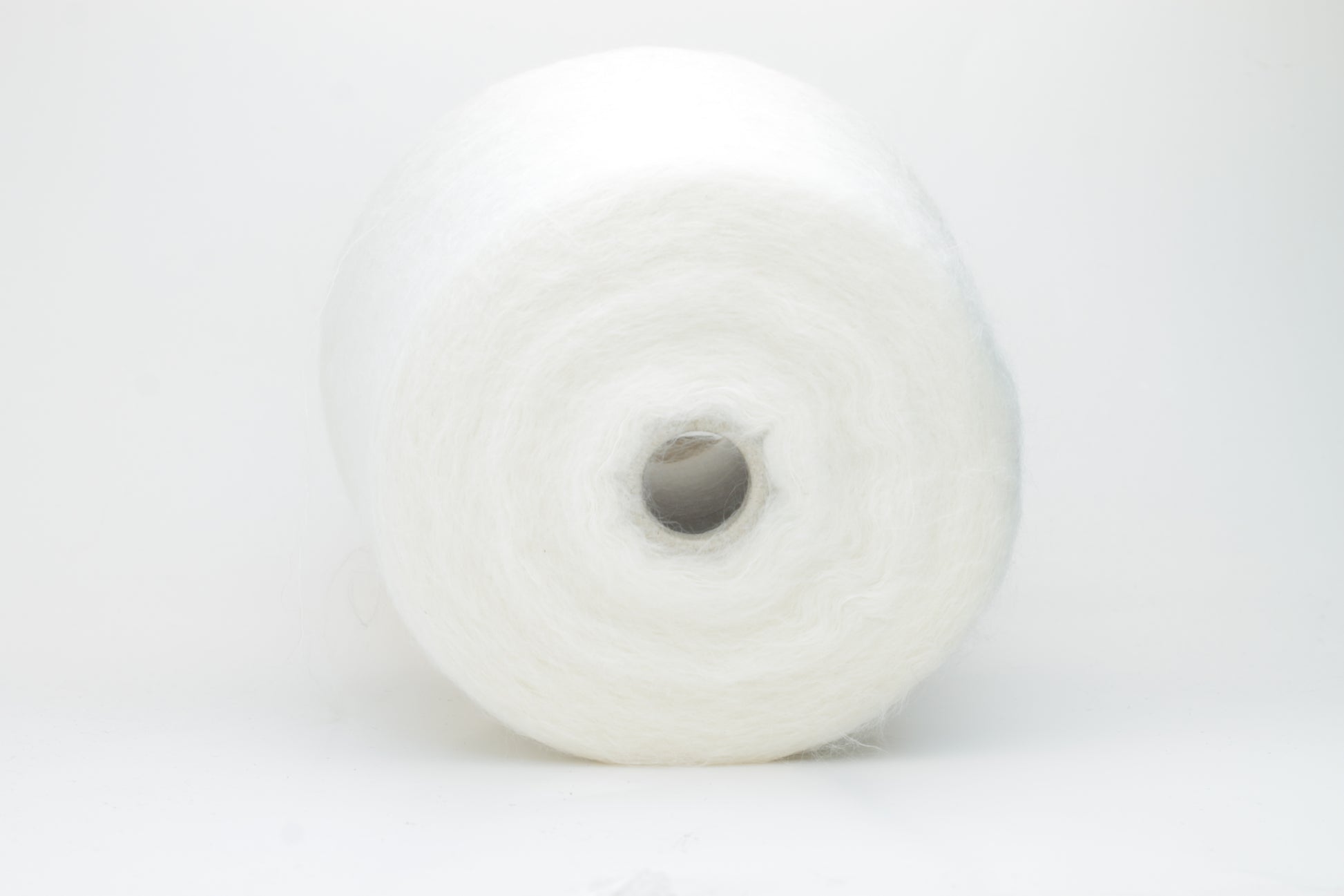 Close-up view of SuperKidMohair yarn in Aurora White color, showcasing its fluffy texture and subtle sheen. The yarn exhibits a smooth ply twist with a rich color depth.