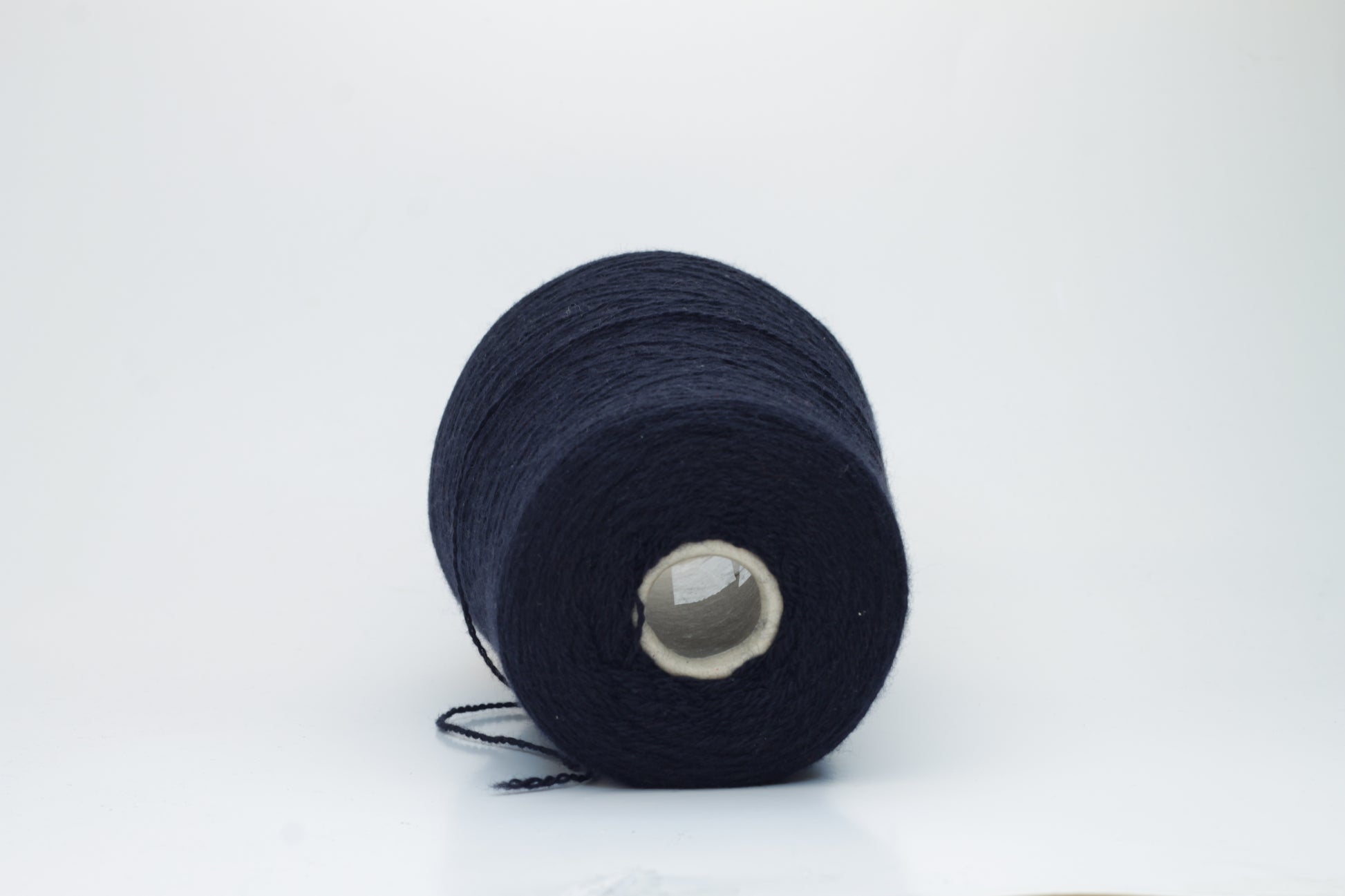 Luxurious, evenly spun two-ply yarn in a deep, rich matte navy blue. The cashmere fibers exhibit a soft halo and subtle natural sheen.