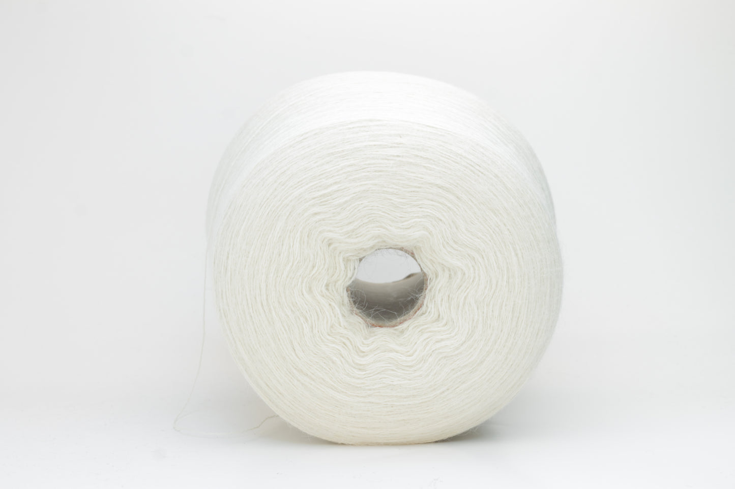A close-up shot of a single ply, pure white alpaca yarn, softly twisted, showcasing its ethereal fluffiness and subtle sheen against a neutral background.