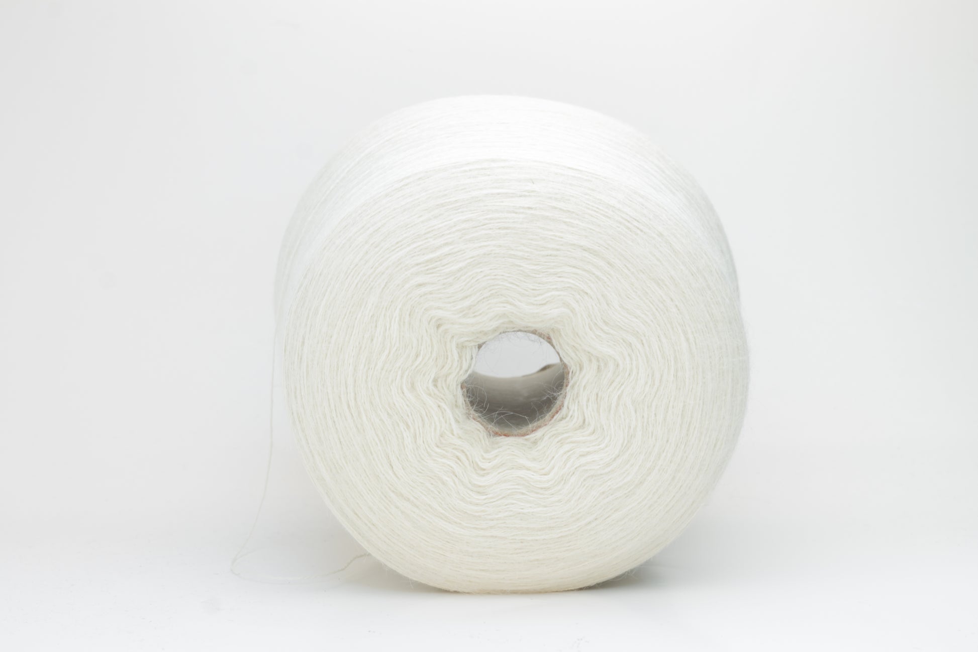 A close-up shot of a single ply, pure white alpaca yarn, softly twisted, showcasing its ethereal fluffiness and subtle sheen against a neutral background.