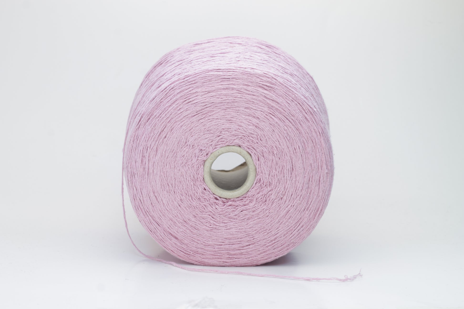 Close-up of luxurious silk bourette yarn in a vibrant 'Rosa Antic' shade. The thread exhibits a fine ply twist with a subtle sheen and remarkable fluffiness, showcasing the yarn’s rich color depth.