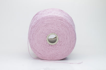 Close-up of luxurious silk bourette yarn in a vibrant 'Rosa Antic' shade. The thread exhibits a fine ply twist with a subtle sheen and remarkable fluffiness, showcasing the yarn’s rich color depth.