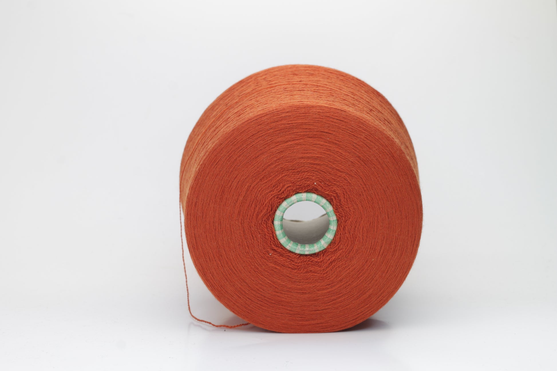 Close-up of luxurious Terra Cotta Merino wool yarn, two-ply twist with a soft, subtle sheen, and fine, consistent thread structure.