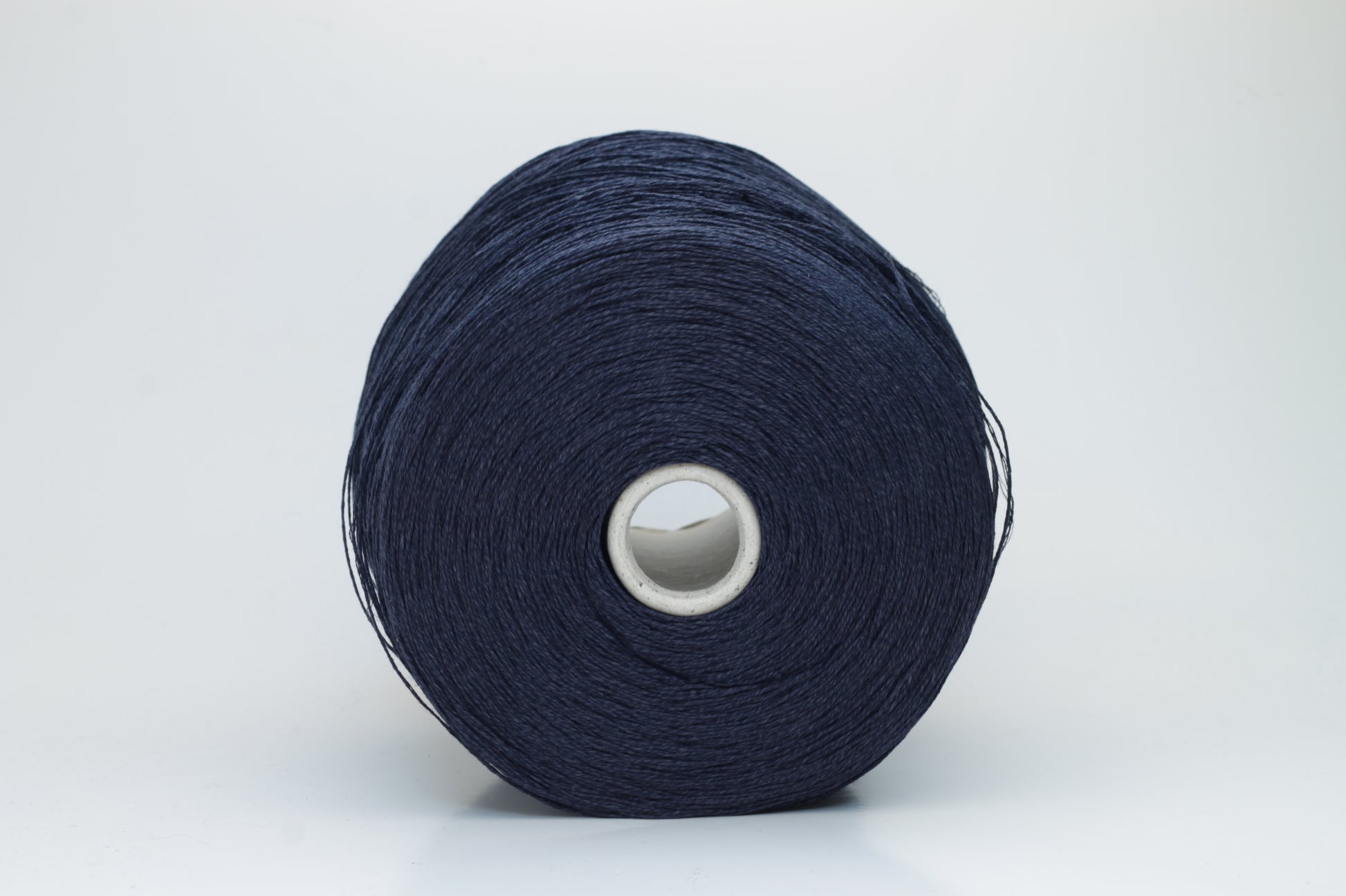 Close-up of pristine Navy linen and viscose blend yarn, softly twisted with a subtle sheen, showcasing its fine, smooth texture.