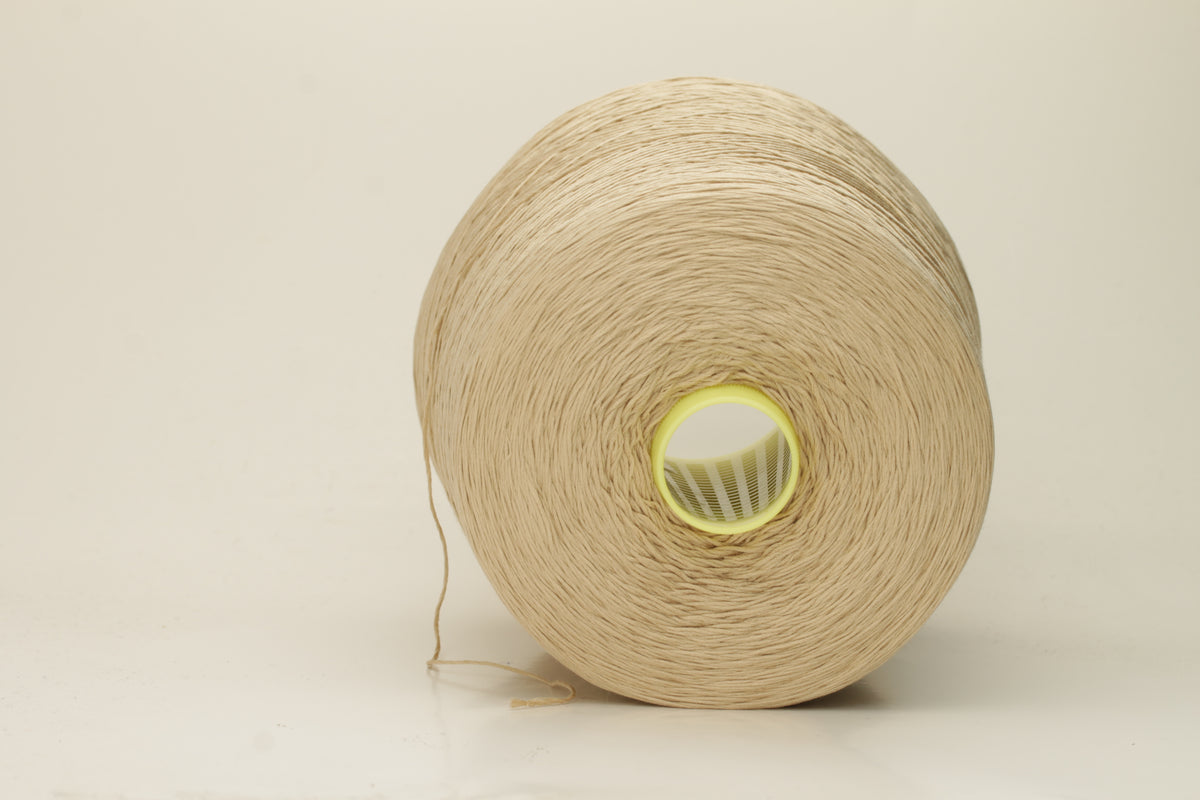 Close-up of a single strand of lustrous, fine-gauge beige silk and cotton yarn, showcasing its smooth, even twist and soft sheen.