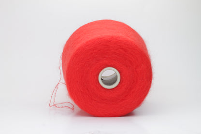 Close-up view of vibrant red SuperKidMohair yarn featuring a dense, fluffy pile with subtle sheen. The ply twist is evident in the slightly twisted structure, creating a soft and luxurious tactile experience.
