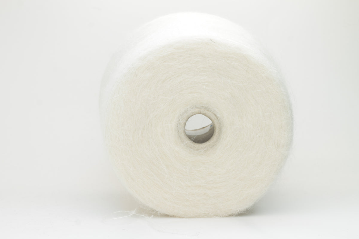 Close-up of pristine white SuperKidMohair Silk yarn, revealing its delicate halo, subtle sheen, and fine, even ply twist.