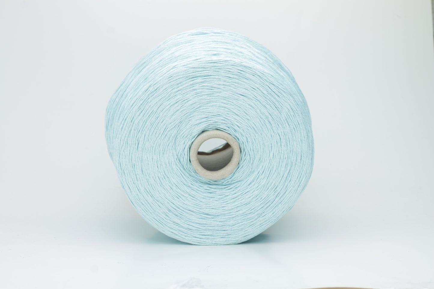 Close-up of fine, natural Linuzzo-colored 100% linen yarn, showing its smooth, slightly matte texture and subtle ply twist, coiled loosely.