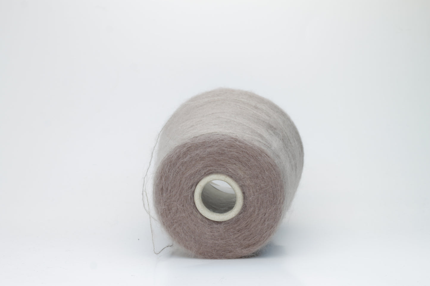 Close-up of fluffy Beige kid mohair and silk blend yarn, subtly lustrous with a soft halo, gently twisted into a fine, delicate thread.
