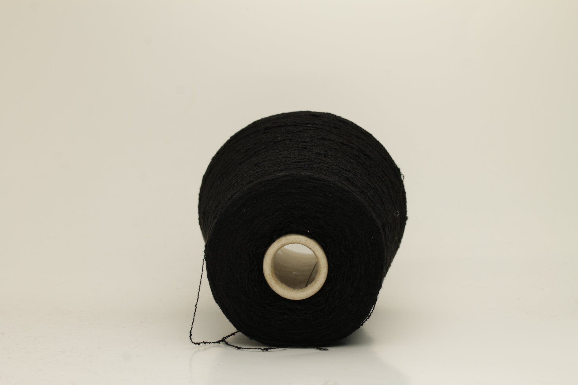 Close-up of a Black, textured Nodino yarn, showing subtle, irregular nubs and a soft, matte sheen; twisted ply visible.