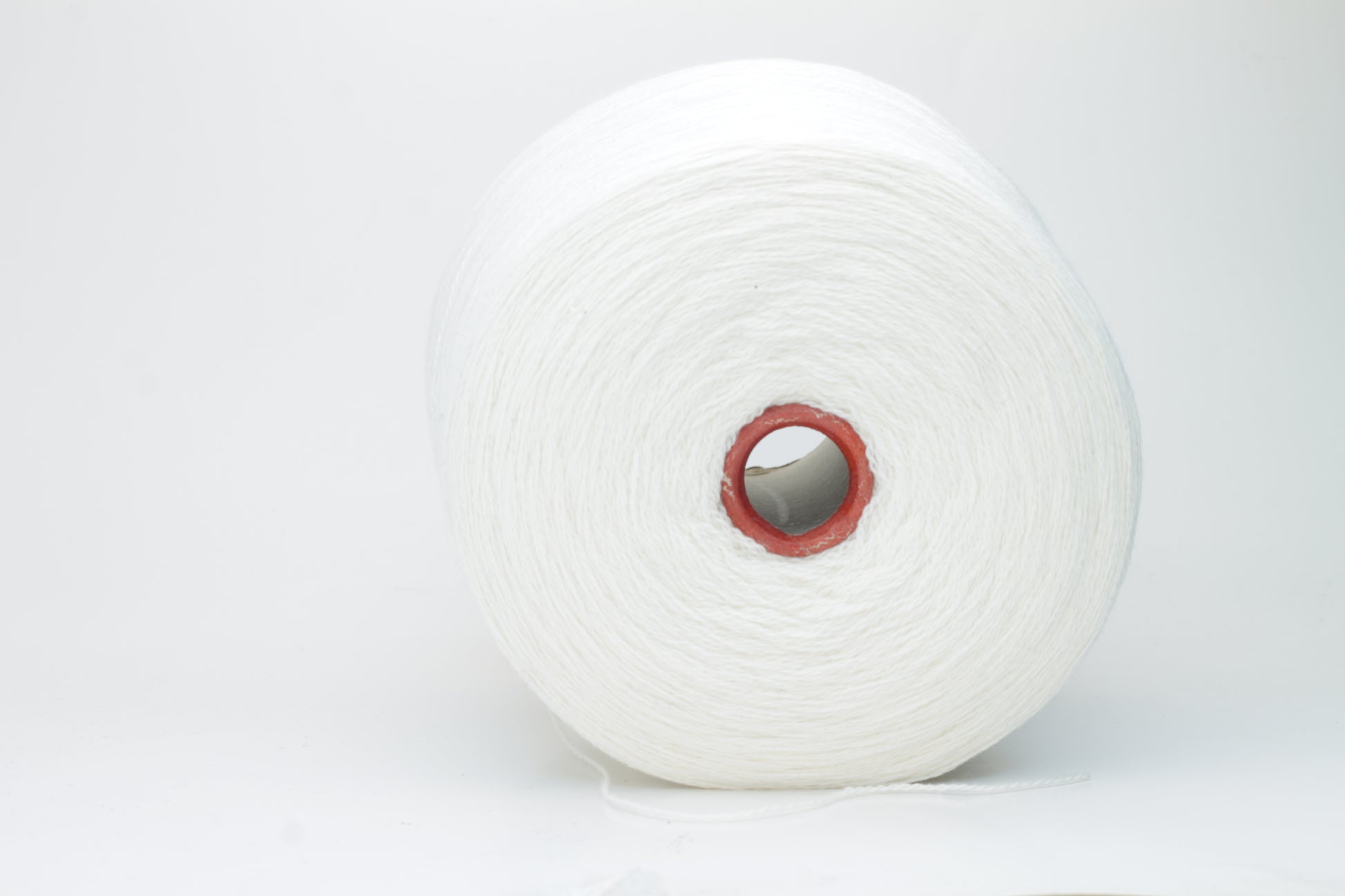 Close-up of pristine white, finely plied 100% cashmere yarn, showcasing its soft halo and subtle sheen on a neutral background.